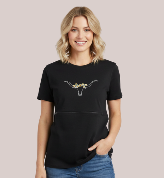 Woman wearing a black short-sleeve customizable nursing t-shirt with a discreet front zipper access, featuring a white custom longhorn skull with yellow daisy flowers.