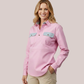 Model wearing a light pink long-sleeve customizable women's nursing shirt with a collar, quarter placket, and contrasting light blue chest pocket flaps.