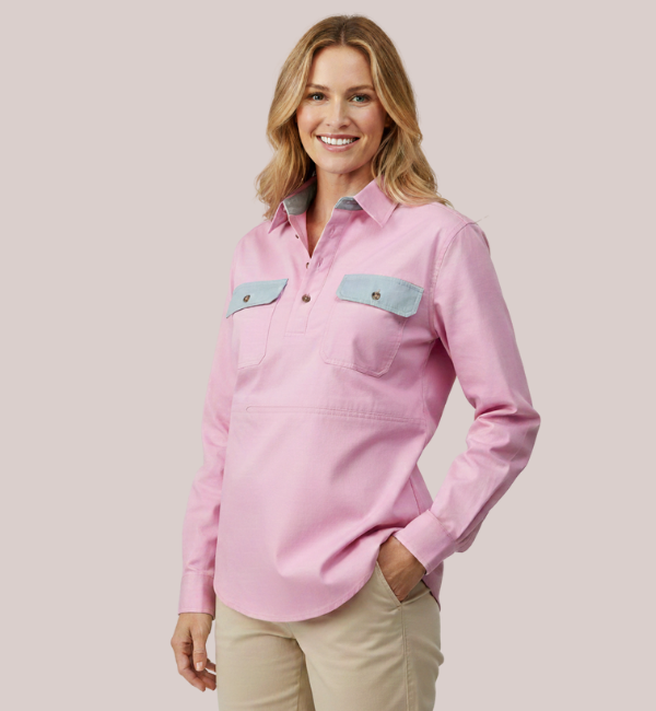 Model wearing a light pink long-sleeve customizable women's nursing shirt with a collar, quarter placket, and contrasting light blue chest pocket flaps.