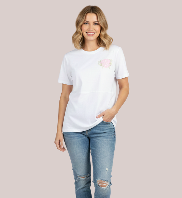 Woman wearing a white short-sleeve customizable nursing t-shirt with a lift-up flap, featuring a custom pink and green floral embroidery design.